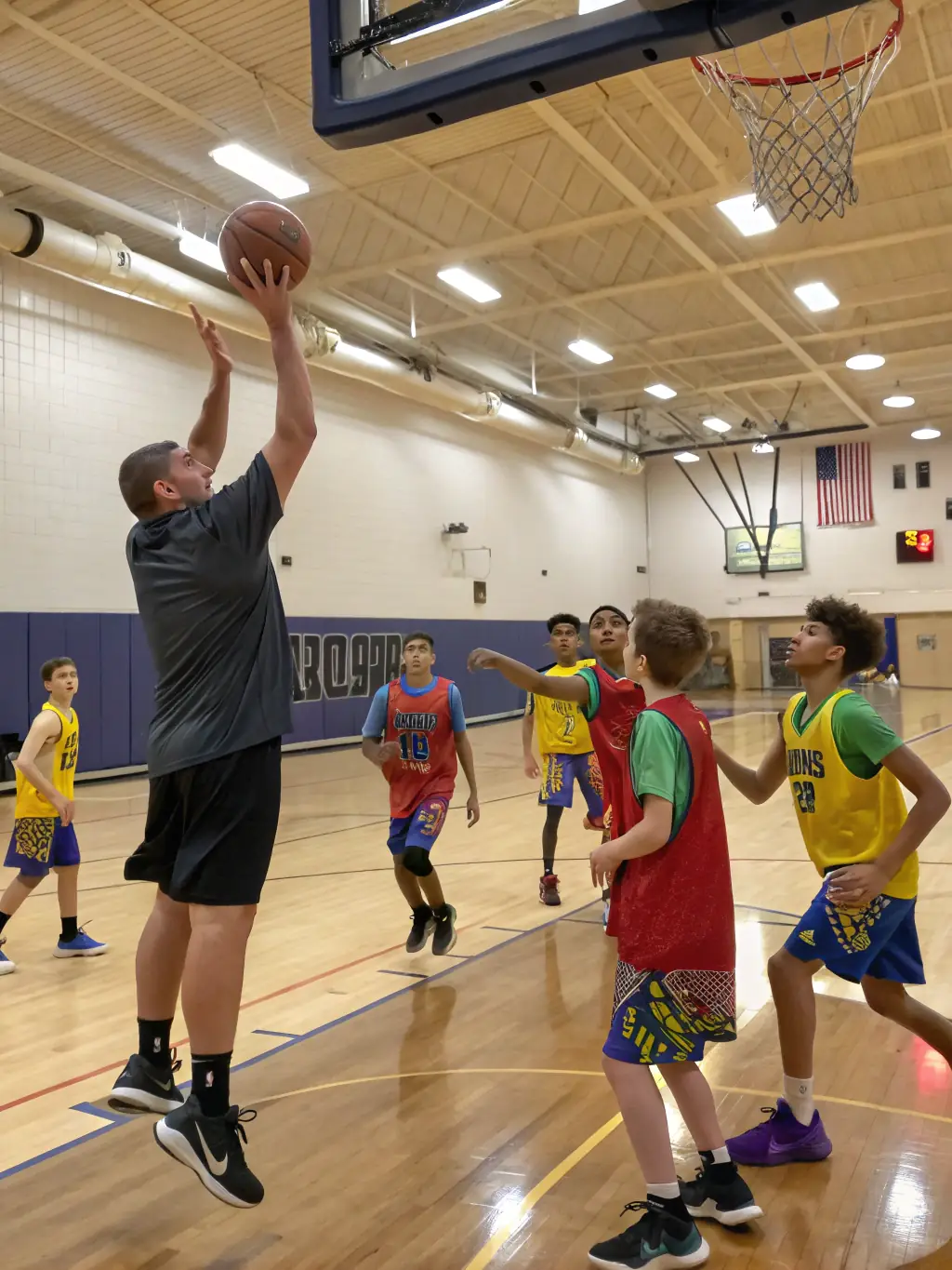 Teenagers engaged in a basketball game, emphasizing agility, strategic thinking, and competitive spirit, within the indoor gymnasium of CLUB ATHLETIQUE BALMANAIS.